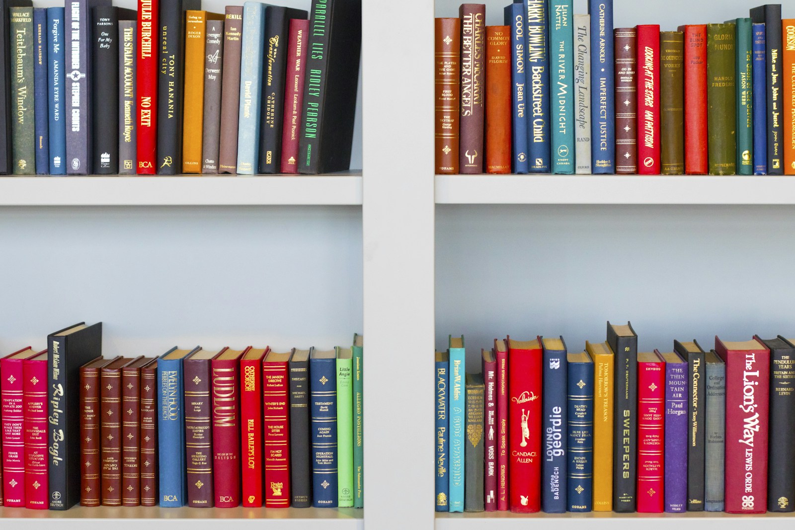 كتب ملونة مصفوفة على رفوف مكتبة بيضاء